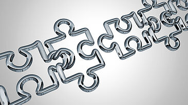 Bild zeigt ineinandergreifende Puzzleteile im Metallic-Look