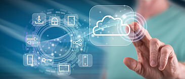 Auf dem Bild tippt eine Person auf ein Cloud-Symbol, daneben sind verschiedene Icons zum Thema IT kreisförmig angeordnet
