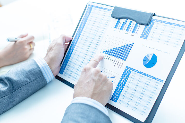 Image shows a person pointing to a chart in a financial report.