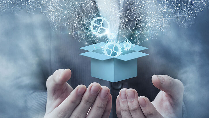 Abbildung zeigt eine Box, die über den Händen einer Person schwebt und aus der Zahnräder und Linien herauskommen