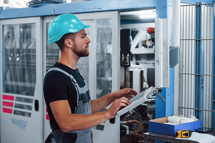Das Foto zeigt einen Produktionsmitarbeiter mit Sicherheitshelm