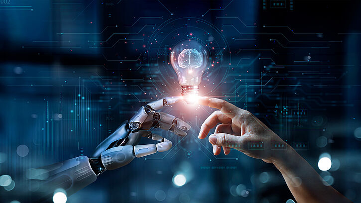 Image shows a robotic hand and a human hand touching each other