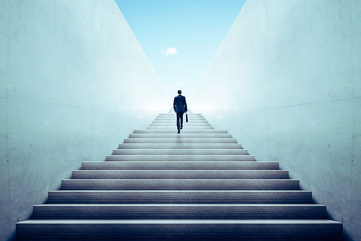 Abbildung zeigt eine Person von hinten, die Treppen hinaufsteigt