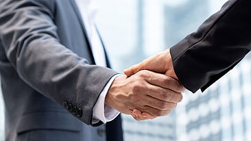 Bild zeigt einen Handschlag zwischen zwei Personen in Business Kleidung
